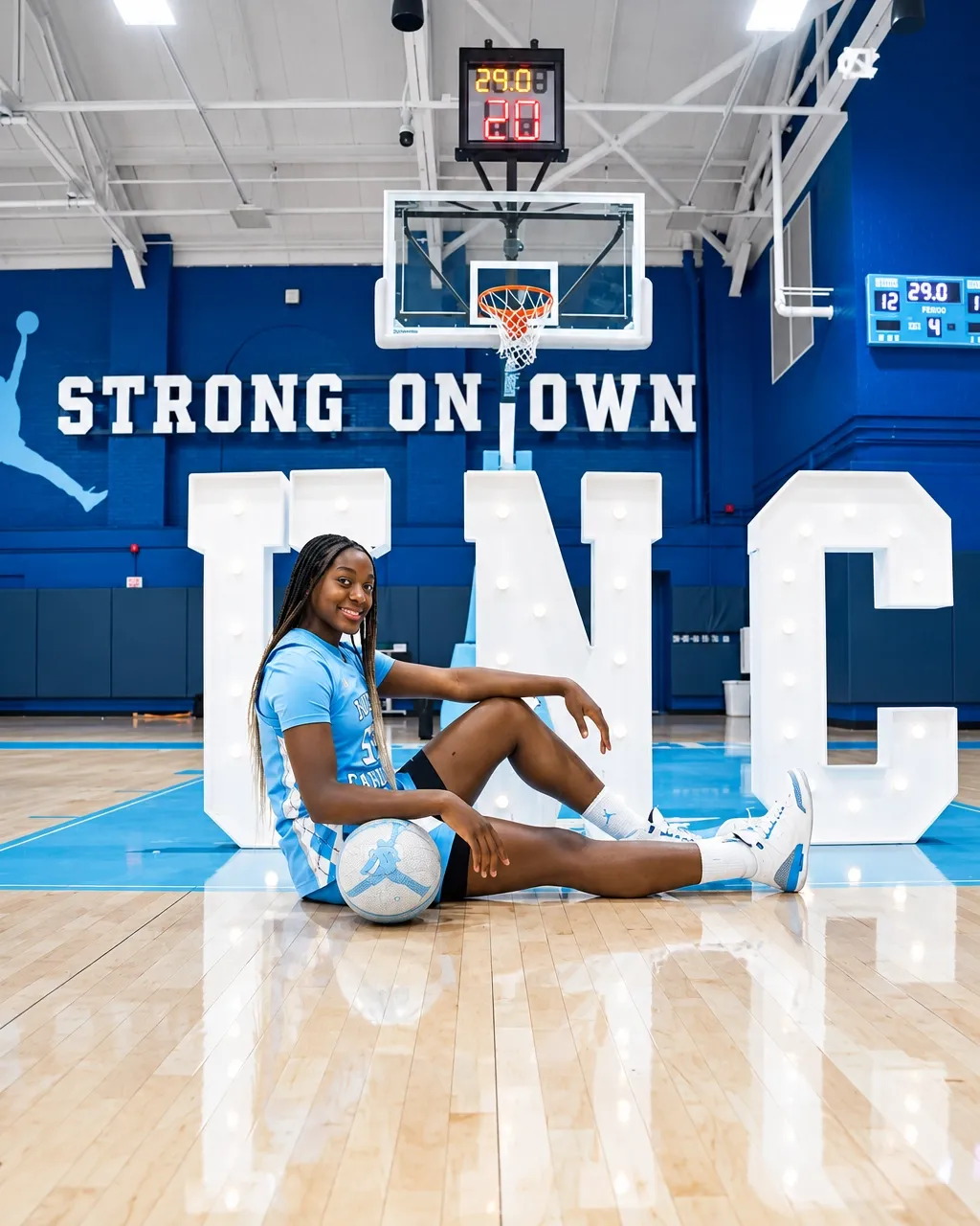 Noelle Bofia seated on the court beside giant North Carolina letters
